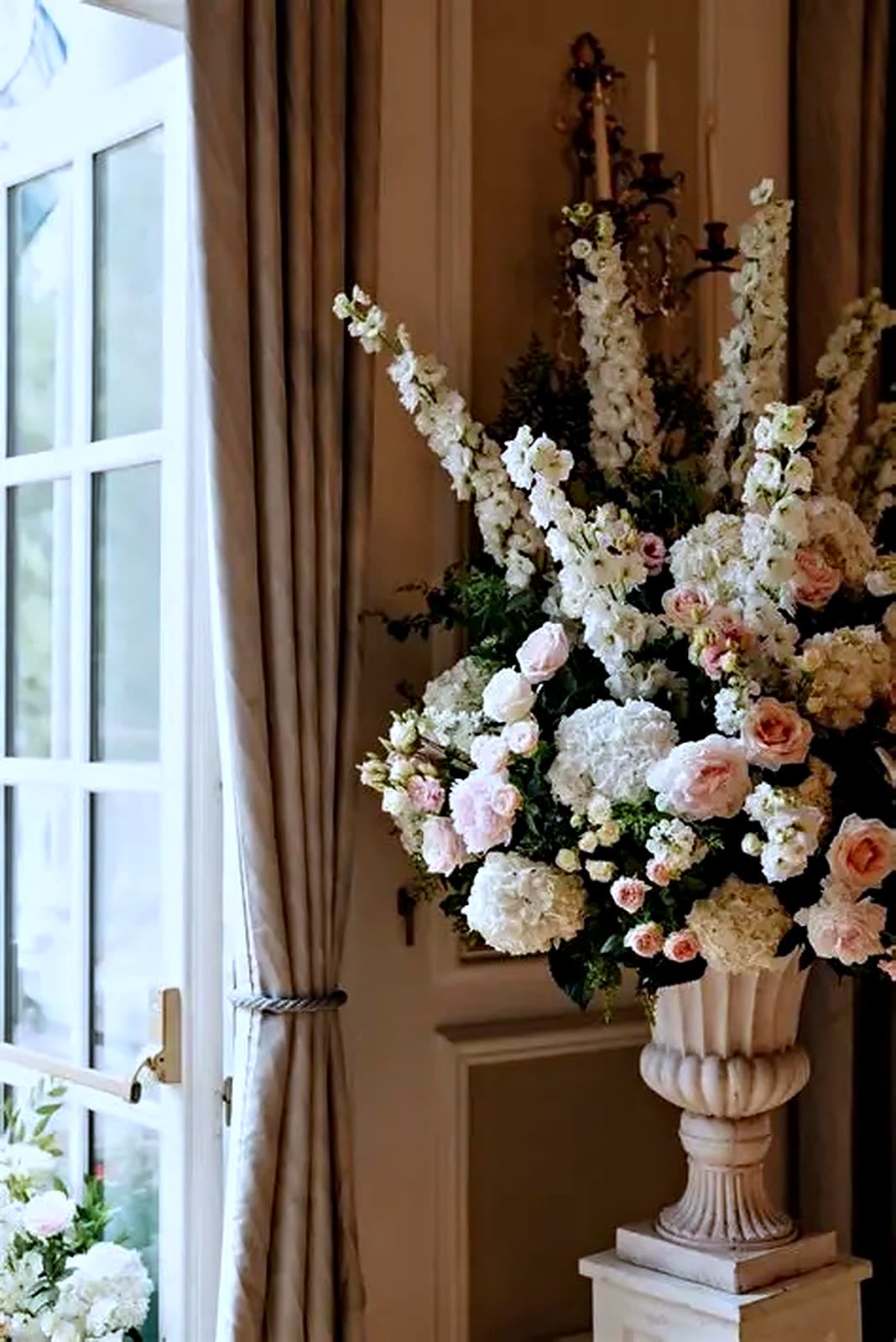 Tall cream and blush arrangement in a stone urn